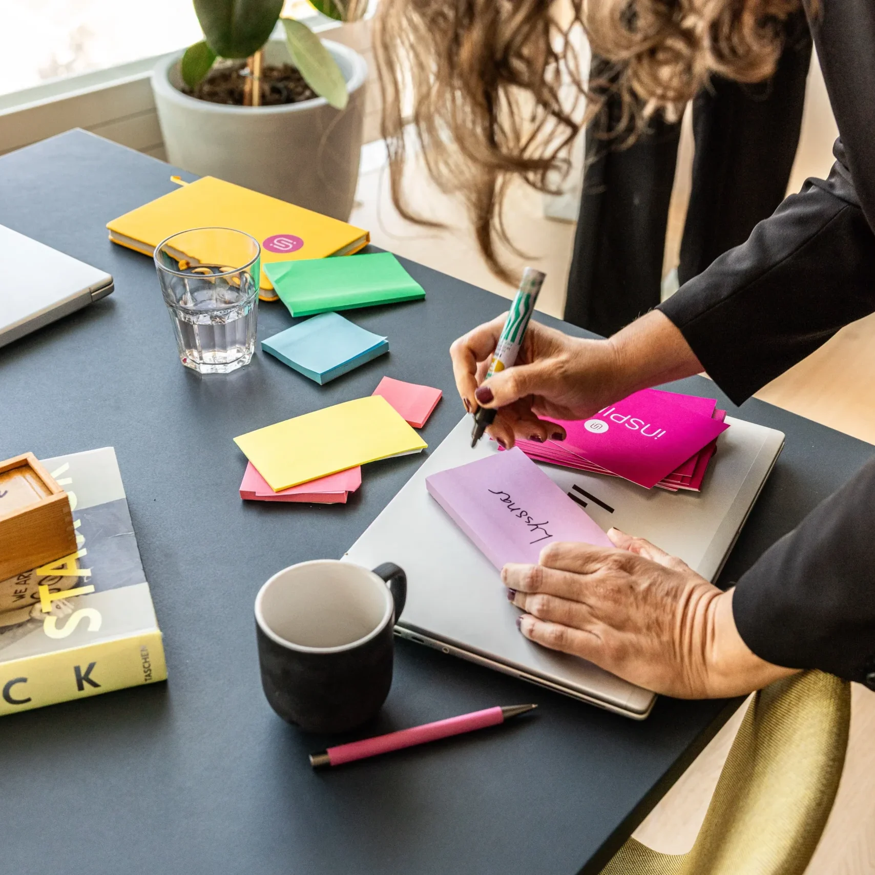 Kvinna skriver på postit-lappar på ett skrivbord