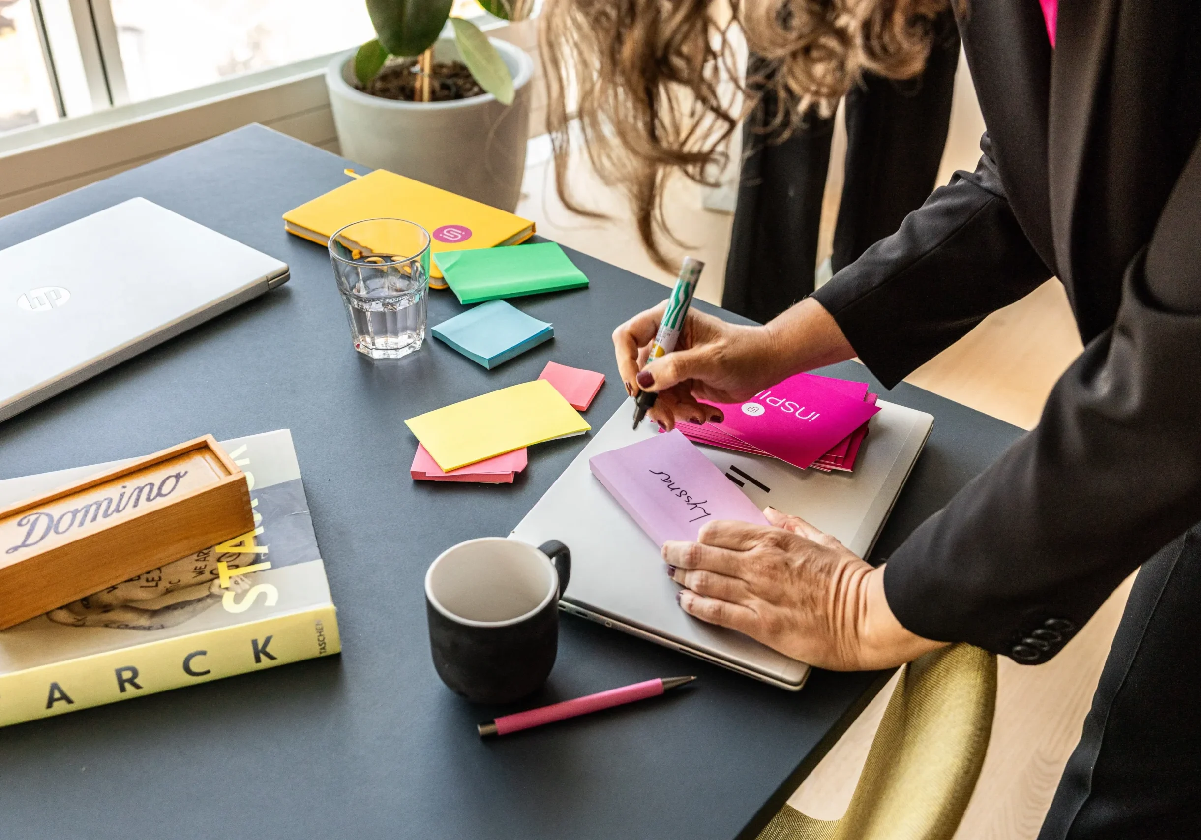 Kvinna skriver på postit-lappar på ett skrivbord