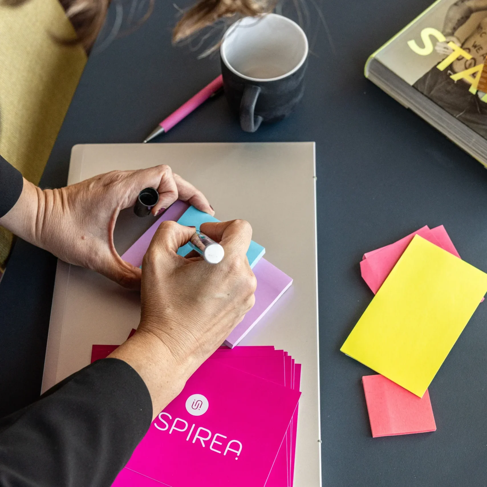 Kvinna skriver på postit-lappar på ett skrivbord